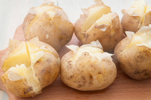 Steaming jacket potatoes cut open with a knob of butter on top 